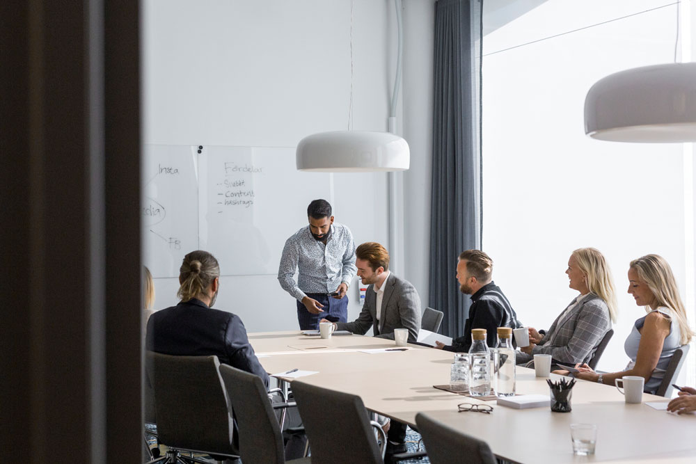 Flera personer som sitter i ett mötesum på ett kontor.